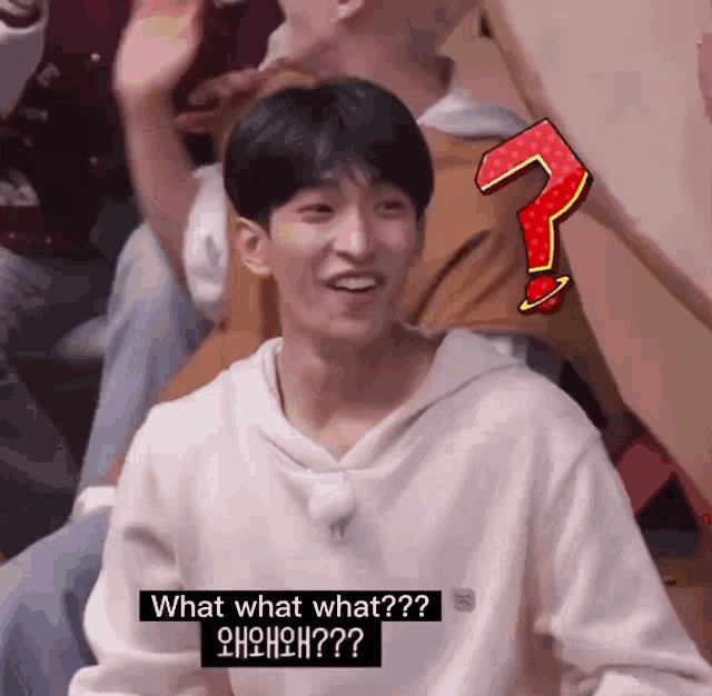 a young man is sitting in a crowd with a question mark on his back and says what what what ?