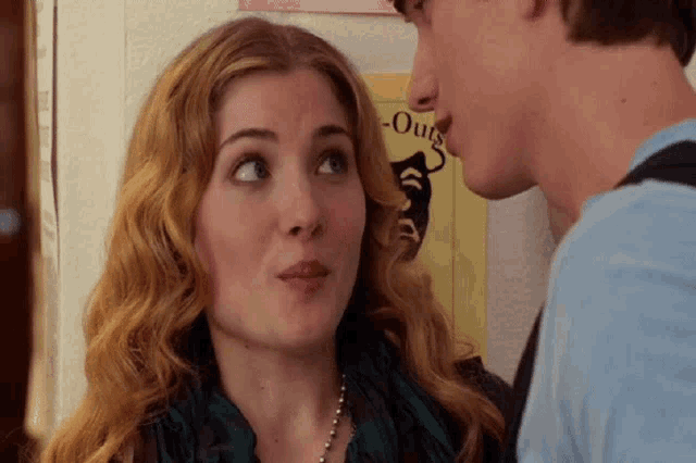 a man and a woman are looking at each other in front of a poster that says " outs "