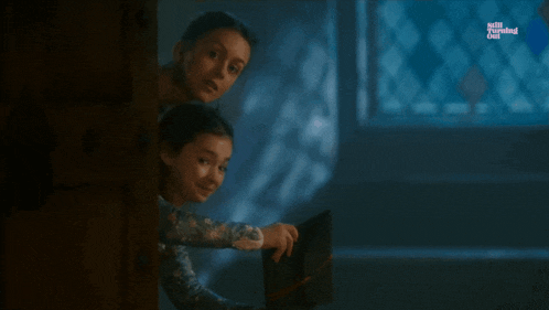 two girls peeking out from behind a door in a dark room with netflix written on the bottom