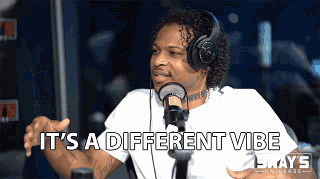 a man wearing headphones talks into a microphone with the words it 's a different vibe below him