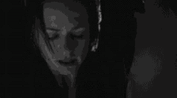a black and white photo of a woman in a dark room .