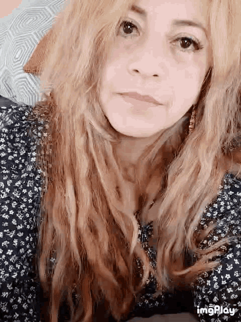 a woman with long blonde hair is wearing a black and white floral top