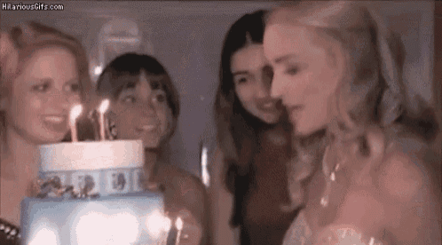 a group of women are blowing out birthday candles on a cake .