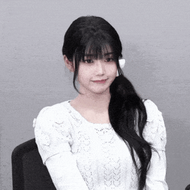 a woman with long black hair is wearing a white top