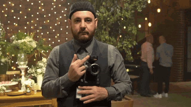 a man with a beard holds a camera in his hands