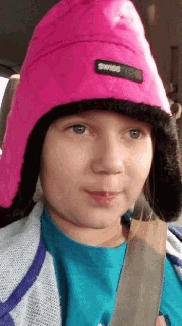 a young girl wearing a pink hat that says swiss tech on it