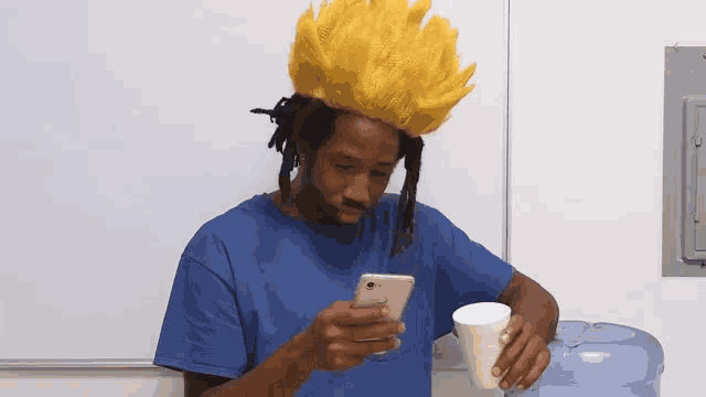 a man wearing a yellow wig is looking at his cell phone