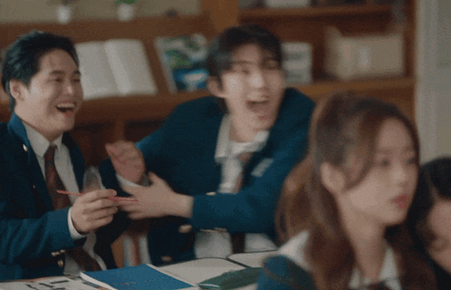 a group of people are laughing in a classroom and one of them is wearing a jacket that says ' a '