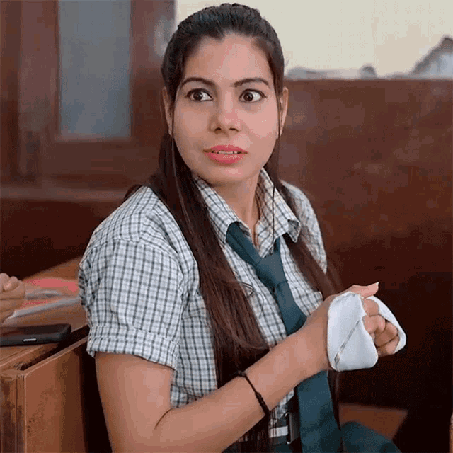 a girl in a plaid shirt and tie is holding a white cloth