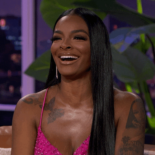 a woman in a pink dress is smiling and has a tattoo on her arm that says ' i love you '