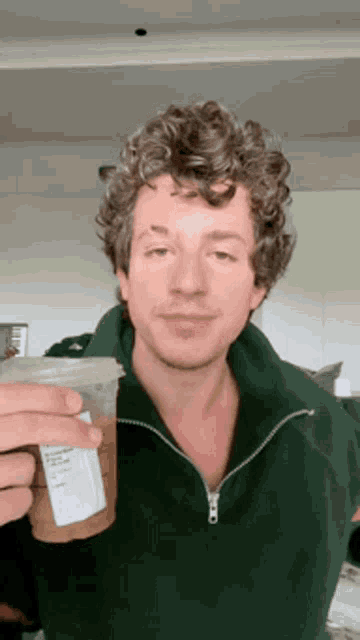 a man in a green jacket is holding a cup of coffee