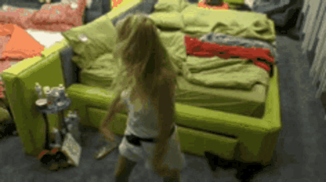 a woman is dancing in a room with a green bed