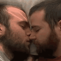 two men with beards are kissing each other on the cheek .