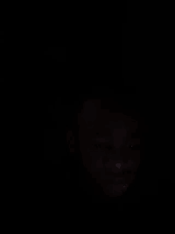 a person 's face is visible in the dark with a blurred background