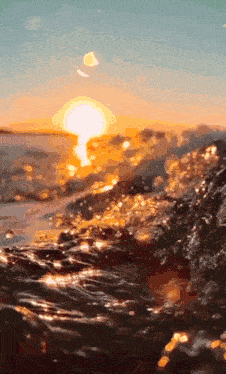 a sunset over a body of water with waves crashing against the rocks