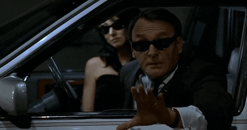 a man in a suit is driving a car with the words enlevez-lui le rose du jambon on the bottom