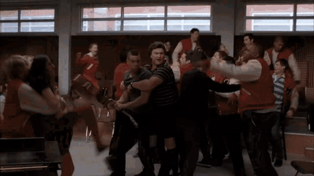 a group of people in red varsity jackets are dancing together