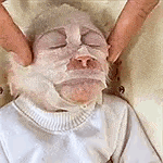 a person is holding a person 's face with a mask on it .