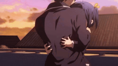 a man and a woman are hugging each other in front of a roof .