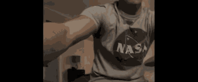 a man wearing a nasa shirt is taking a selfie .