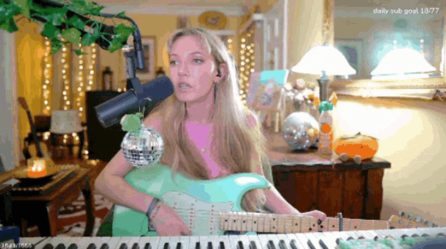 a woman singing into a microphone while playing a guitar and keyboard
