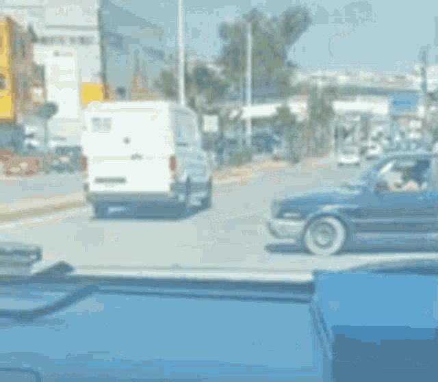 a black car is driving down a street in a city