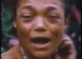 a close up of a woman 's face with her mouth open and a pearl necklace .