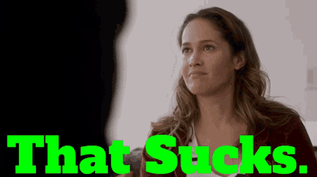 a woman sitting in front of a green sign that says that sucks