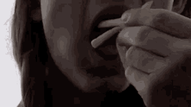 a close up of a woman eating french fries with chopsticks .