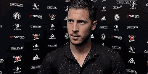 a man in a black shirt is standing in front of a wall with chelsea tv written on it