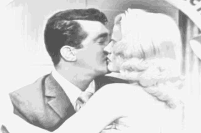 a man in a suit and tie kisses a woman in a white dress