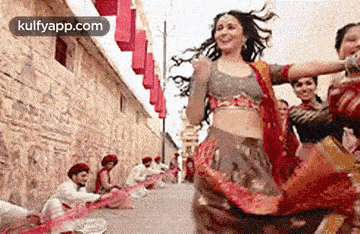 a woman is dancing on a street with a group of people .
