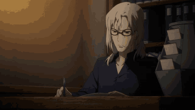 a man with glasses sits at a desk writing in a book