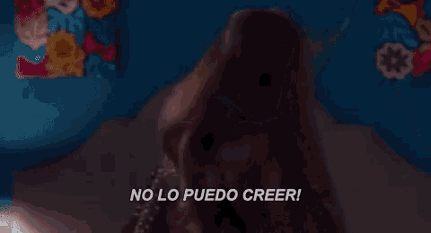 a woman is sitting on a bed and says no lo puedo creer in spanish .