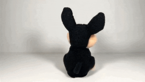a stuffed animal is sitting on a white surface and looking at the camera .