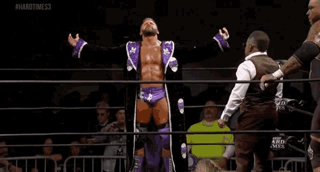 a wrestler named matt cardona is standing in a wrestling ring with his arms outstretched