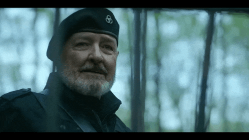 a man with a beard is wearing a black beret with a symbol on it .