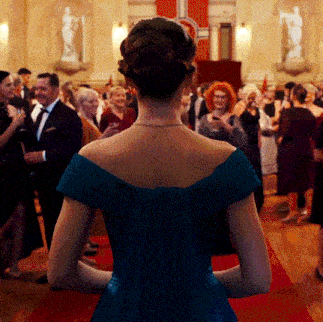 a woman in a blue dress stands in a crowd of people