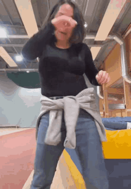 a woman in a black shirt and blue jeans is dancing .