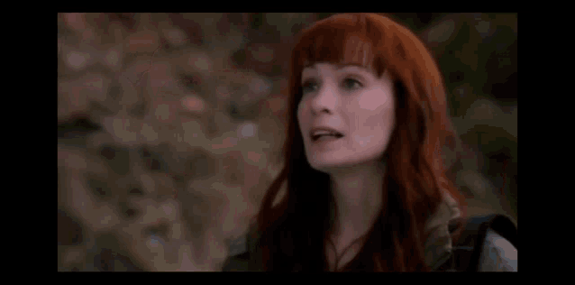 a woman with red hair is smiling in a blurry photo