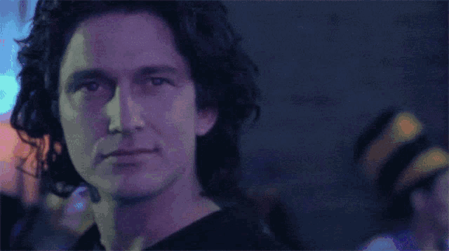 a close up of a man 's face with purple lights behind him