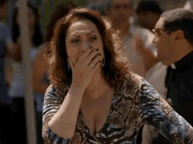 a woman covering her mouth with her hand while standing in a crowd