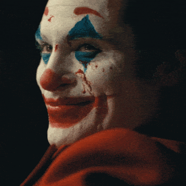 a close up of a clown 's face with red and blue paint on it