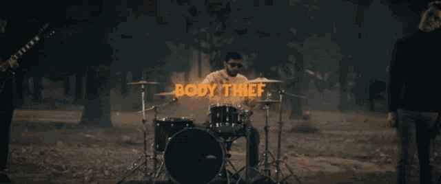 a man playing drums with the words body thief written above him