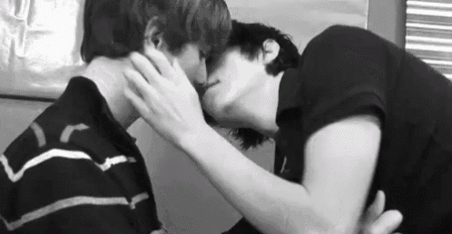a couple of men are kissing each other in a black and white photo .