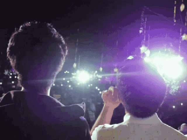 a couple of people standing in front of a purple light