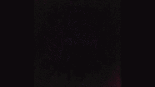 a blurred image of a person in a dark room with purple and blue lights