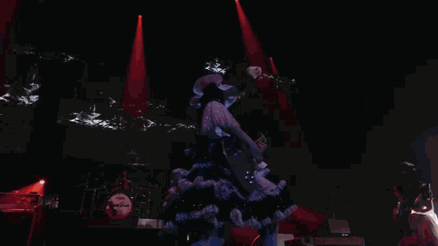 a woman in a red dress is singing into a microphone while another woman plays a guitar