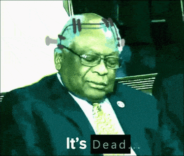 a man in a suit and tie is sitting in a dark room and says it 's dead .