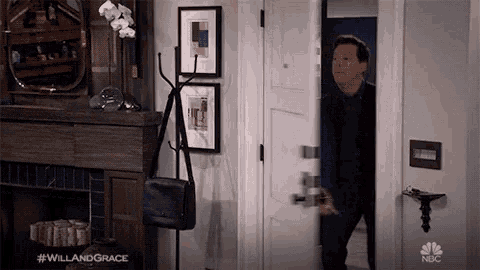 a man standing in a doorway with #willandgrace on the bottom right